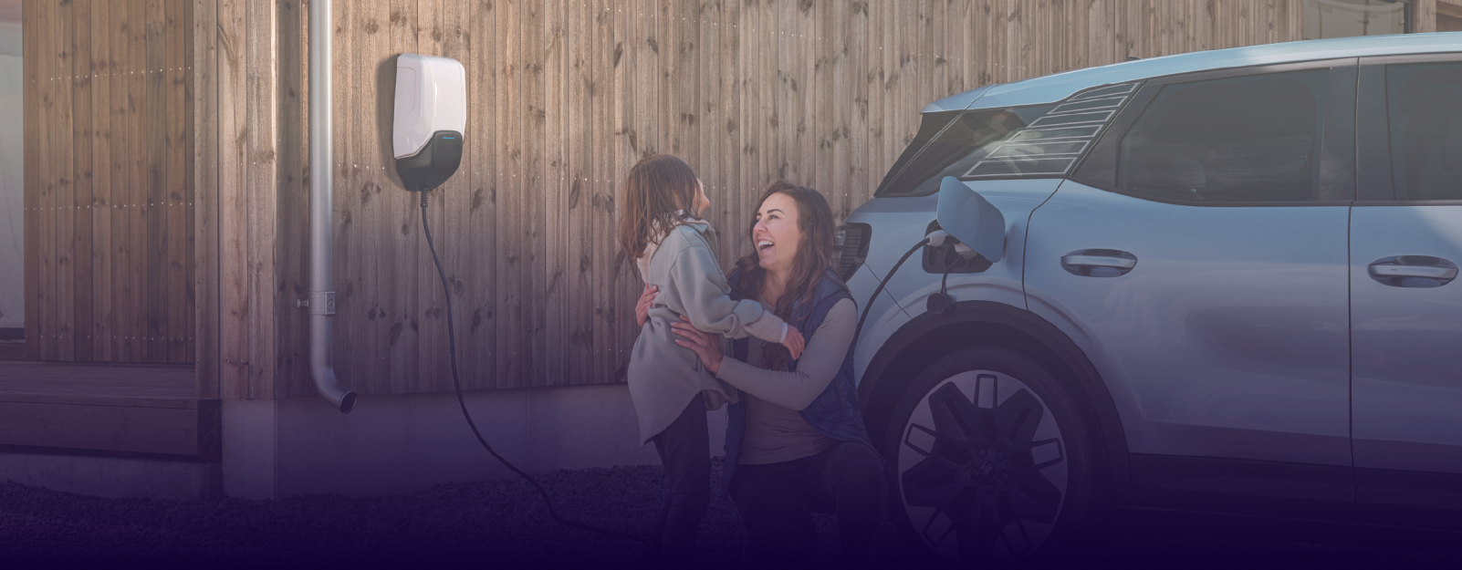 Mother and daughter hugging next to charging Ford EV